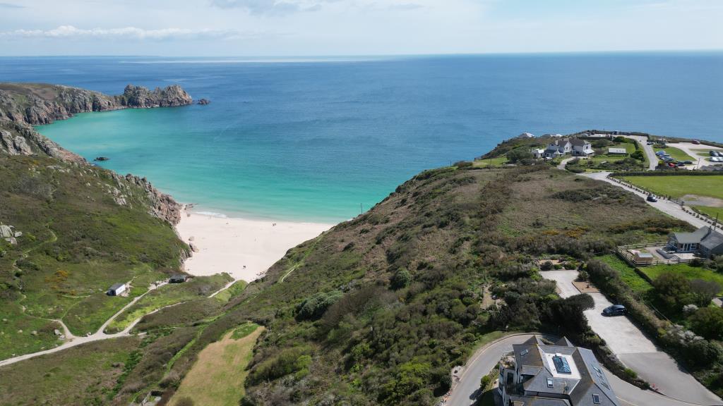 Lot: 69 - DETACHED RESIDENTIAL PROPERTY ENJOYING BREATHTAKING SEA VIEWS IN TRULY STUNNING LOCATION - Drone photo overlooking Porthcurno beach, properties land and part of the Minack